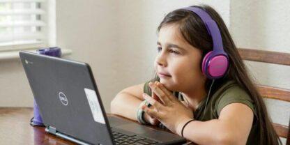 A student wearing headphones and working on a laptop.
