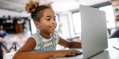 Young girl sitting at a table using a laptop
